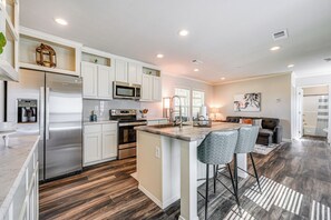 A modern kitchen with white cabinets, stainless steel appliances, and a central island with bar stools. - Lovely Broken Bow Cottage w/ Hot Tub & Fire Pit! (Broken Bow)