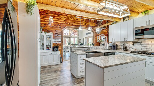 A spacious kitchen with wooden beams, white cabinetry, and a large island. - Expansive Mountain Home Rental w/ Yard & Fire Pit! (Mountain Home)