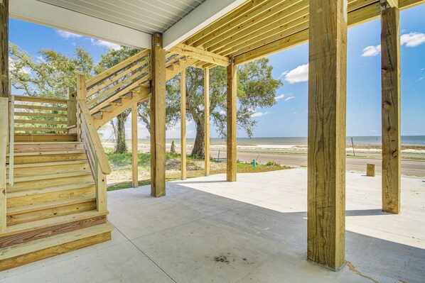 Un escalier en bois mène à un espace extérieur abrité, d’où l’on a une vue sur la plage et l’océan.