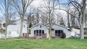Une maison de plain-pied avec une terrasse à l’avant, un garage et un petit porche.