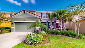 A two-story house with a garage, a well-maintained lawn, and palm trees. - Beautiful 5 Bed Pool Home With Game Room 5 Bedroom Home by RedAwning (Davenport)