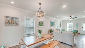A dining area with a wooden table and bench, a chandelier, and artwork on the walls. - Near State Parks: Carrabelle Home w/ Beach Access! (Carrabelle)