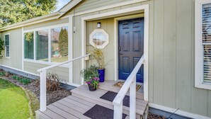 A house with a front porch, a dark blue door, and a small garden with potted plants. - Idyllic Rock Island Home w/ Columbia River Views (Rock Island)
