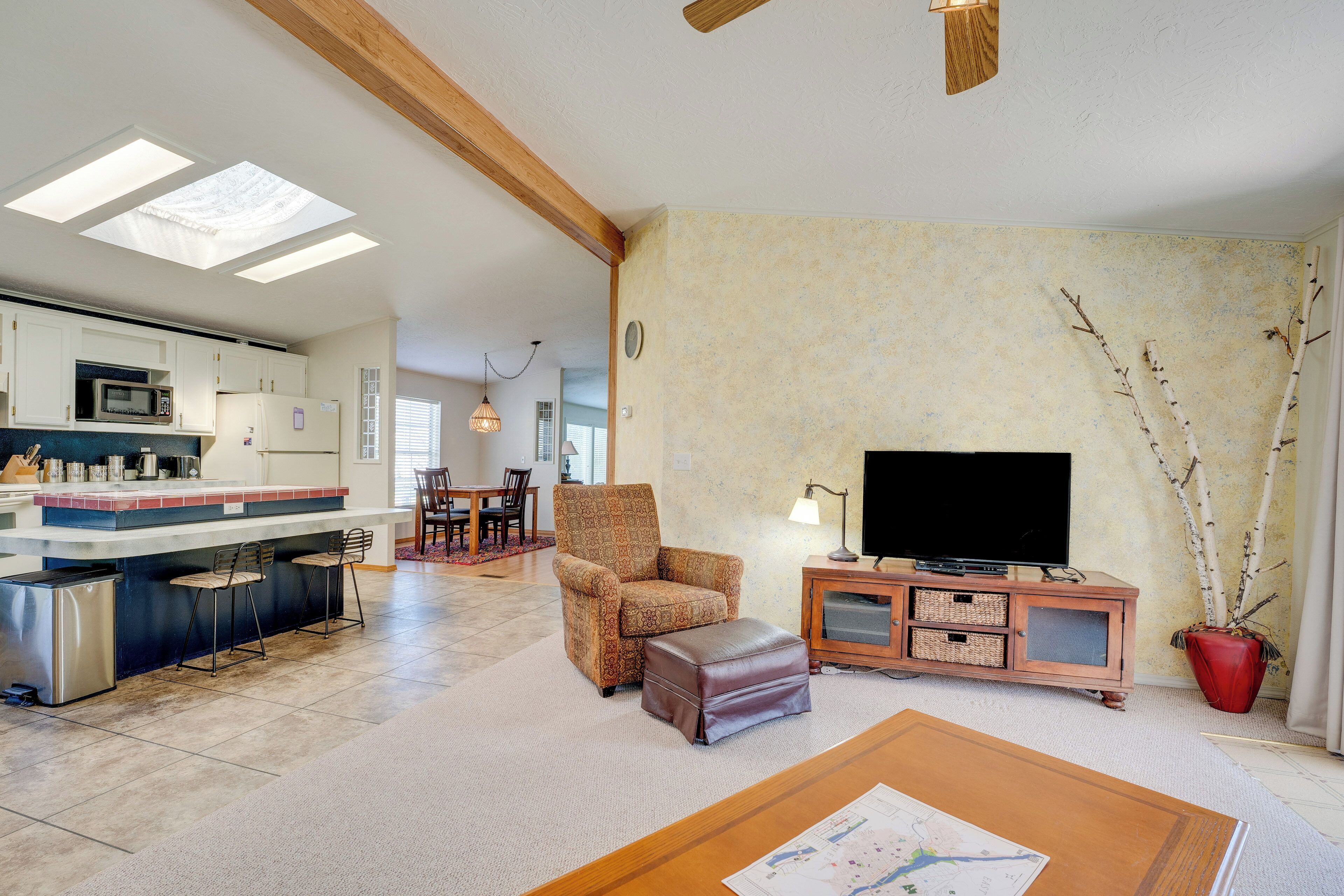 A spacious living area with a kitchen, a comfortable armchair, a television, and a dining area.