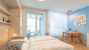 Quarto moderno com uma cama grande, uma mesa de jantar e vista para o exterior.