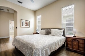 A bedroom with a large bed, two bedside tables, a nightstand, a framed picture on the wall, and a door leading to another room. - Beautiful 5 Bed Pool Home In Reunion 5 Bedroom Home by RedAwning (Kissimmee)