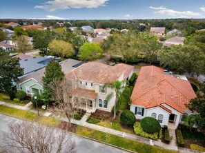 A residential area with houses featuring red-tiled roofs, surrounded by greenery and a clear sky. - Beautiful 5 Bed Pool Home In Reunion 5 Bedroom Home by RedAwning (Kissimmee)