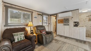 A cozy living area with leather sofas, a lamp, and a wooden wall with a sign. - Gone Fishin 2 Bedroom Cabin by RedAwning (Kimberling City)