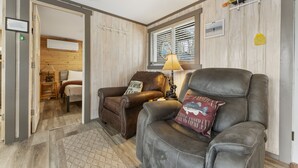 A cozy living room with two leather chairs, a lamp, and a wooden wall. - Gone Fishin 2 Bedroom Cabin by RedAwning (Kimberling City)