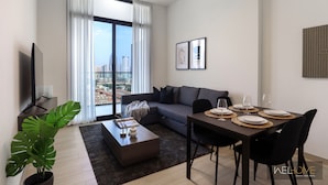 A modern living room with a sofa, dining table, and a large window with curtains.