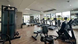 A modern gym with treadmills, elliptical machines, and weightlifting equipment.