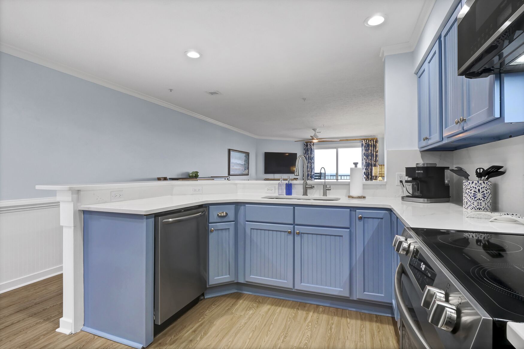 A kitchen with blue cabinets, a black stove, and a white countertop.