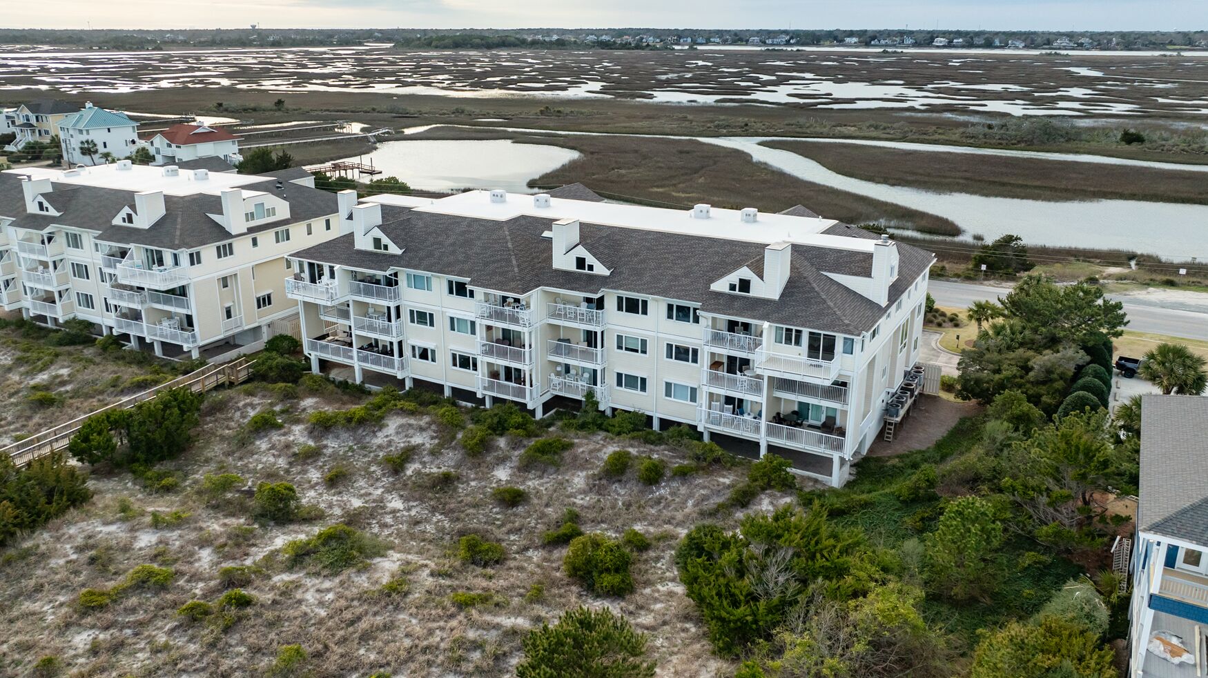 Un hotel de varios pisos con balcones, ubicado en la playa con arena y vista al agua.