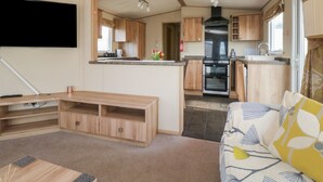 A compact kitchen with wooden cabinets, a black stove, and a small island. - A La Mer (Paignton)