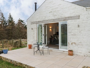 Een wit bakstenen huis met een terras, een tafel en stoelen.