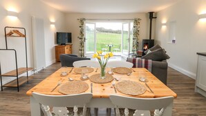A dining area with a table set for four, a sofa, a TV, and a fireplace. - The Barn (Bishop Auckland)