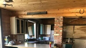 Une cuisine avec un plafond en bois, un mur d’accent en briques et un îlot central doté de placards.