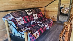 Un intérieur chaleureux de cabane en bois, avec un canapé matelassé, une table en bois et une ambiance rustique.