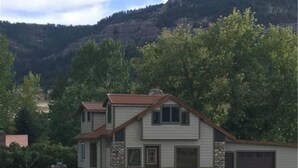 Une maison à deux étages avec des fondations en pierre, un garage et une grande cour avant.