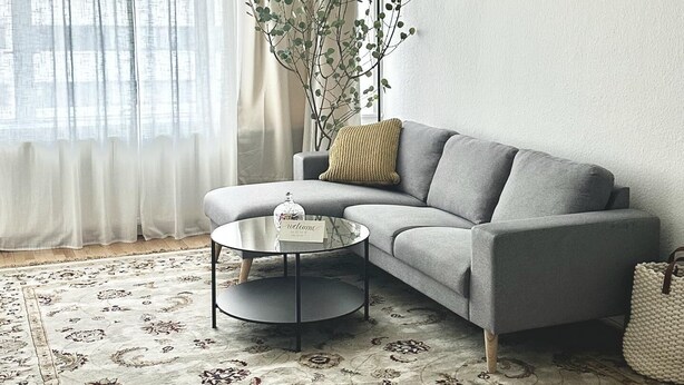 A modern living room with a grey sofa, a round coffee table, a floor lamp, and a patterned rug. - Captivating 2-bed Apartment in Viby J (Aarhus)