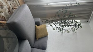 A grey sofa with a woven throw pillow, a glass coffee table, and a branch with green leaves. - Captivating 2-bed Apartment in Viby J (Aarhus)