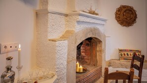 Una habitación con chimenea, pared blanca, silla de madera y un cojín decorativo.