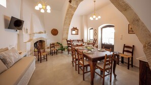 Un comedor con arco de piedra, muebles de madera y chimenea.