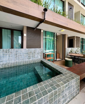 Une piscine extérieure moderne, dotée de bords carrelés, d’une terrasse en bois et d’un espace détente avec une table et des chaises.