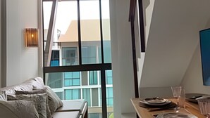 A modern room with a sofa, a dining table with plates, a hanging light fixture, and large windows. - Sunny Hall Flats  (Ipojuca)