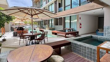 An outdoor patio area with a pool, wooden furniture, and a covered seating area.