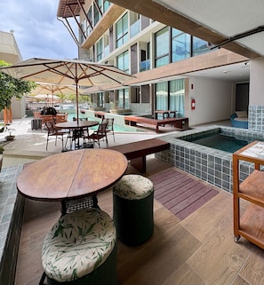 Un espace extérieur aménagé avec une terrasse, une piscine, des meubles en bois et un coin salon abrité.