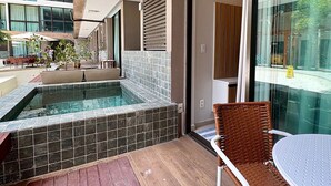 A modern outdoor pool area with a tiled edge, a wooden deck, and a wicker chair. - Sunny Hall Flats  (Ipojuca)