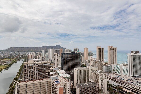 A cityscape with high-rise buildings, a river, and a mountain in the background.