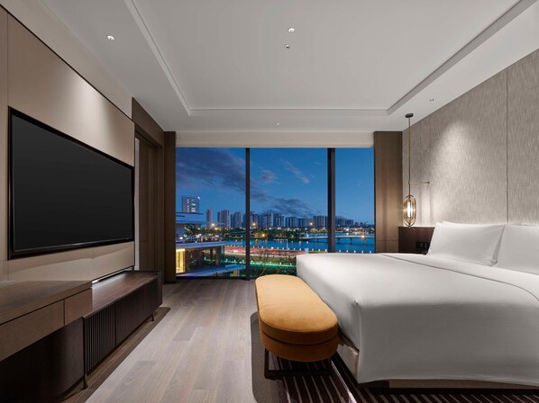 Een moderne hotelkamer met een groot bed, een flatscreen televisie en uitzicht over de stad.