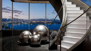 A modern spiral staircase with a city view, surrounded by metallic sculptures. - Hilton Changshu (Suzhou)