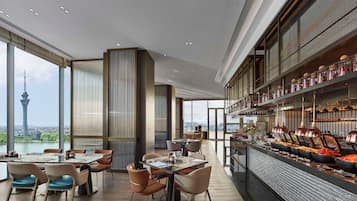 Een modern restaurant met een hoge plafond, grote ramen en een buffetgedeelte.