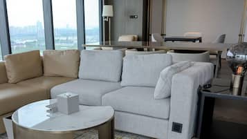 Een moderne woonkamer met een beige bank, een grijze zithoekbank, een ronde salontafel en een flatscreen televisie.