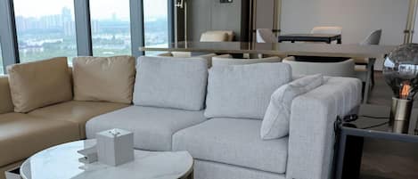 A modern living room with a beige sofa, a grey sectional, a round coffee table, and a flat-screen TV.