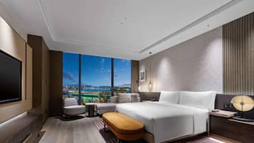 Een moderne hotelkamer met een groot bed, een televisie en uitzicht op een stadsbeeld.