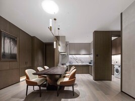 Una cocina moderna con salpicadero de mármol, un comedor con mesa y sillas de madera, y una obra de arte grande enmarcada en la pared.