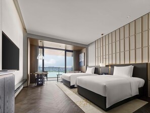 A modern hotel room with two beds, a large window with a city view, a flat-screen TV, and a small table with chairs. - Hilton Changshu (Suzhou)