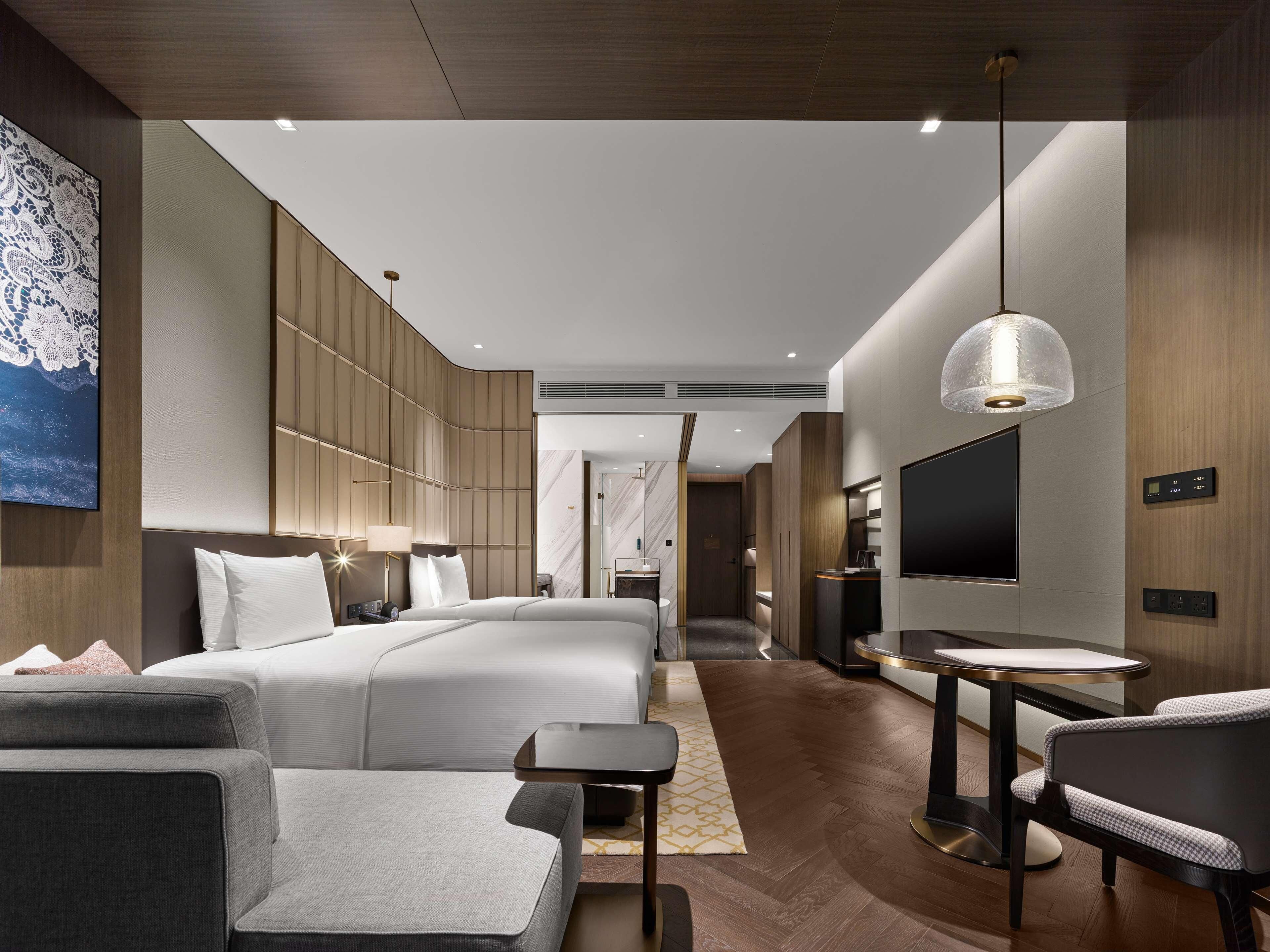 Una habitación de hotel moderna con una cama grande, televisión, escritorio y zona de estar.