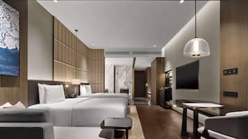 Una habitación de hotel moderna con una cama grande, televisión, escritorio y zona de estar.