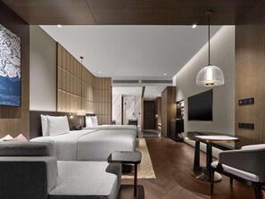A modern hotel room with a large bed, a TV, a desk, and a seating area. - Hilton Changshu (Suzhou)