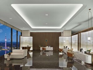 En modern hotellobby med ett stort panoramafönster, en receptionsdisk och en sittgrupp.