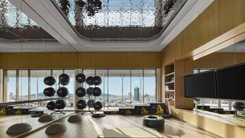A spacious gym with exercise equipment, large windows, and a city view.