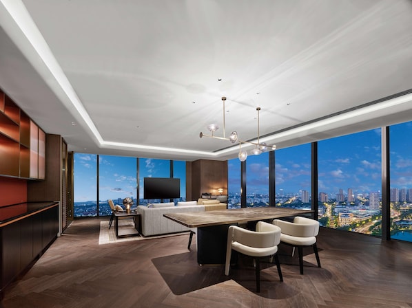 A modern living room with a large city view, a flat-screen TV, and a dining area with a wooden table and chairs. - Hilton Changshu (Suzhou)