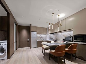 A modern kitchen with a built-in washer, a marble backsplash, and a dining area with two chairs. - Hilton Changshu (Suzhou)
