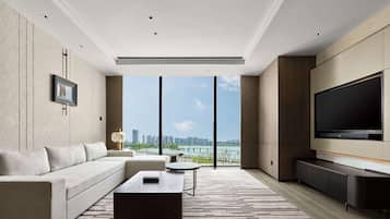 A modern living room with a large TV, a sofa, a coffee table, and a view of a cityscape.