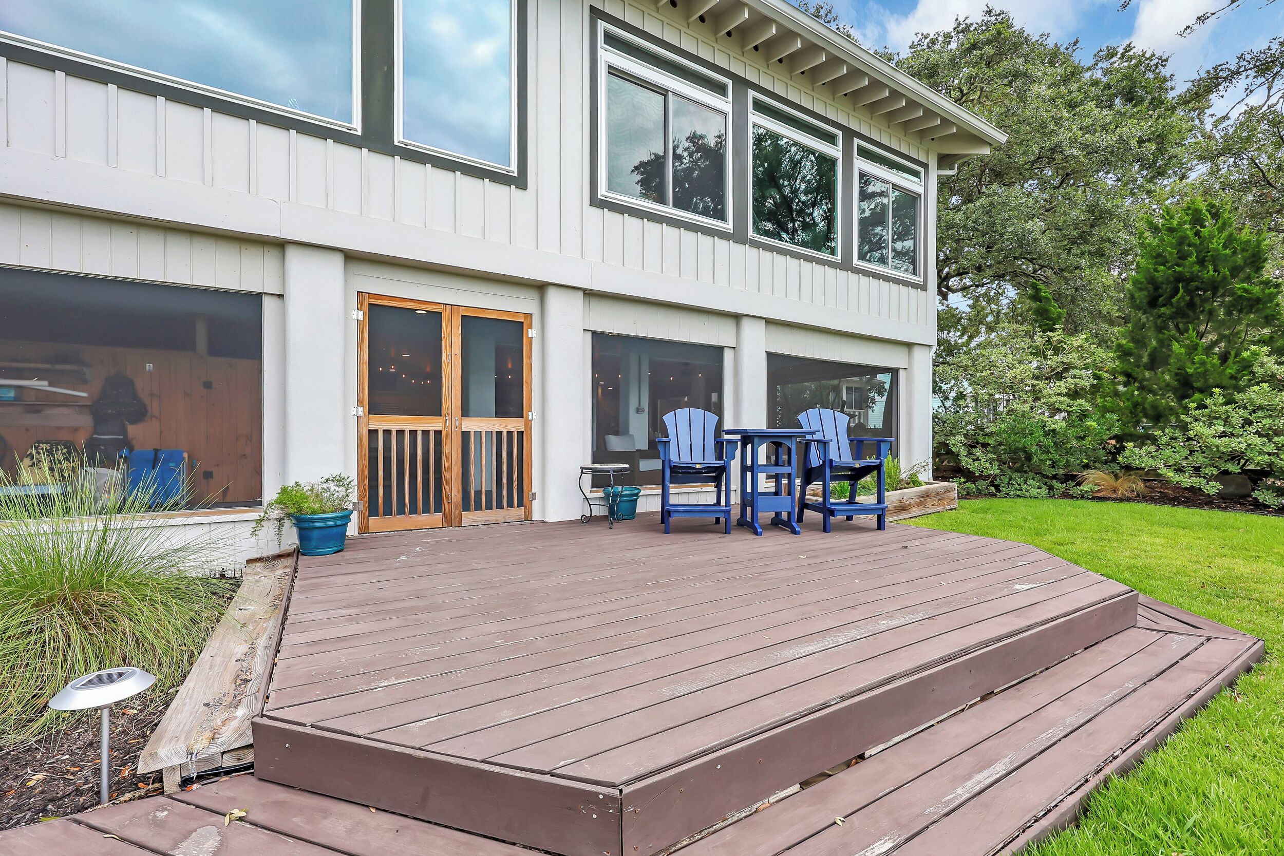 A two-story house with a wooden deck, large windows, and a door.